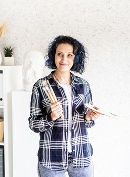 Portrait of a creative woman artist with her palette and painbrushes