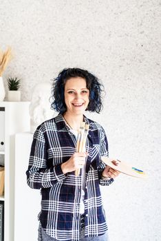 Portrait of a creative woman artist with her palette and painbrushes