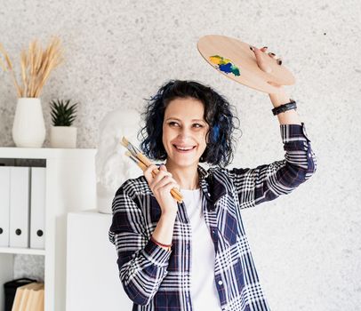 Portrait of a creative woman artist with her palette and painbrushes