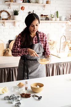 Cooking and baking. Young latin woman whisking eggs cooking at the kitchen