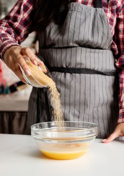 Cooking and baking. Young latin woman pouring sugar to the dough cooking at the kitchen