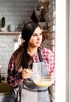 Cooking and baking. Young latin woman whisking eggs cooking at the kitchen