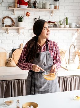 Cooking and baking. Young latin woman whisking eggs cooking at the kitchen