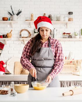 Cooking and baking. Young latin woman whisking eggs cooking at the kitchen