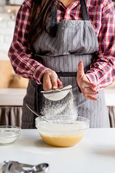 Cooking and baking. Young latin woman pouring flour to the dough cooking at the kitchen