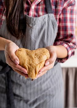 Cooking and baking. Woman hands holding heart shaped dough