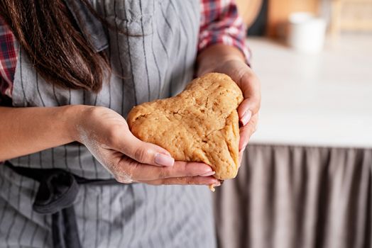 Cooking and baking. Woman hands holding heart shaped dough