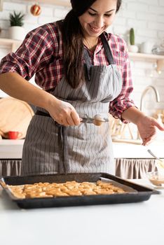 Cooking and baking. Young brunette woman baking cookies at the kitchen