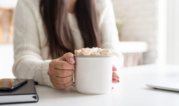 Christmas and New Year. Brunette woman holding a cup of marshmallow cocoa