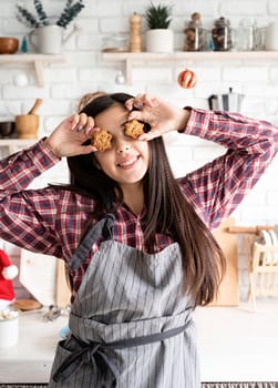 Cooking and baking. Happy woman in apron holding star shaped cookies in front of her eyes