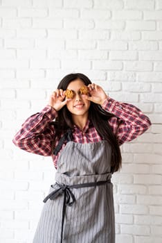 Cooking and baking. Happy woman in apron holding star shaped cookies in front of her eyes