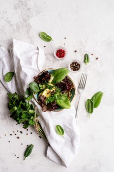 Healthy veggie salad with spinach, red lettuce, cucumbers and greenery top view flat lay