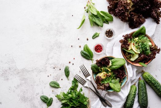 Healthy veggie salad with spinach, red lettuce, cucumbers and greenery top view flat lay with copy space