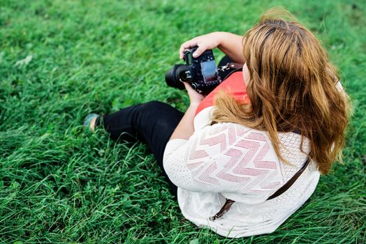 Body positive. Portrait of overweight woman taking pictures with a camera in the park