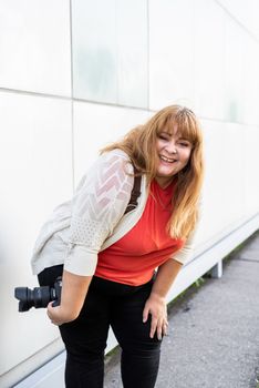 Body positive. Portrait of overweight woman taking pictures with a camera outdoors