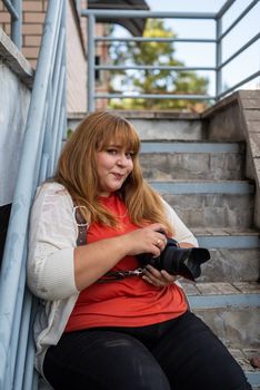 Body positive. Portrait of overweight woman taking pictures with a camera outdoors