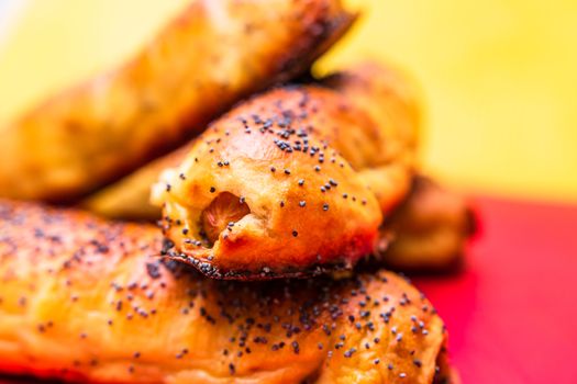 Close up of sausages baked in dough sprinkled with salt and poppy seeds. Sausages rolls, delicious homemade pastries isolated.