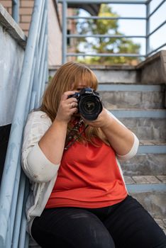 Body positive. Portrait of overweight woman taking pictures with a camera outdoors