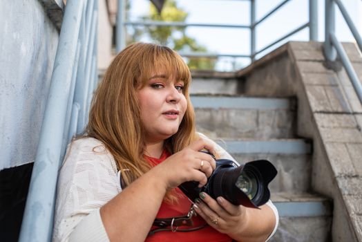 Body positive. Portrait of overweight woman taking pictures with a camera outdoors
