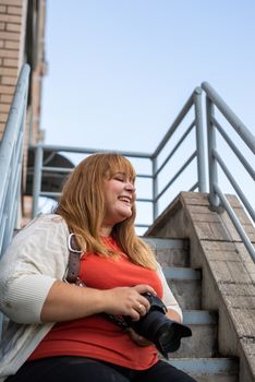 Body positive. Portrait of overweight woman taking pictures with a camera outdoors