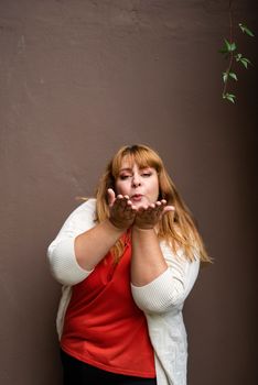 Body positive. Confident overweight woman posing on the brown solid wall on the street