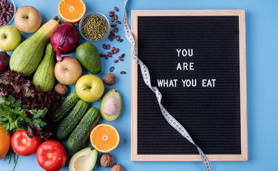 Healthy diet. Fresh vegetables and fruit for healthy diet, measuring tape and black letter board with words You Are What You Eat top view flat lay with copy space