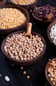 Various dried legumes in wooden bowls on wooden rustic background