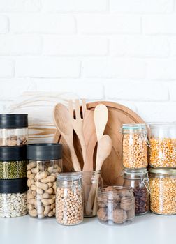 Various dried legumes in wooden bowls top view flat lay on white marble background with copy space