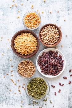 Various dried legumes in wooden bowls top view flat lay on gray rustic background