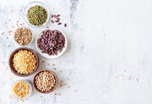 Various dried legumes in wooden bowls top view flat lay on gray rustic background with copy space