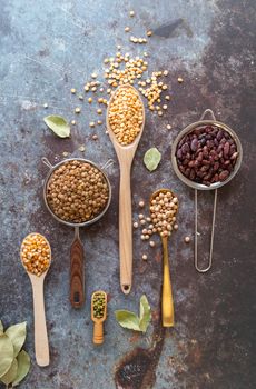 Various dried legumes in spoons top view flat layon dark concrete background