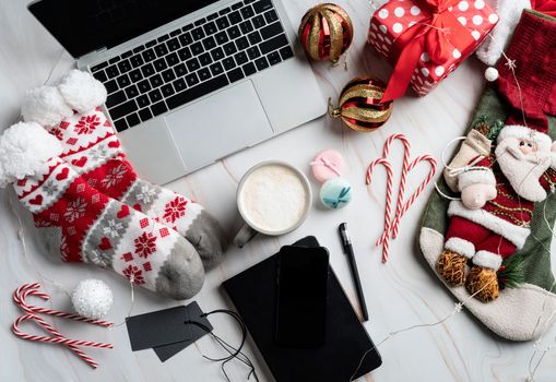 Christmas desktop with laptop, tablet and smart phone surrounded by stockings, candy canes and coffee, top view flat lay, copy space