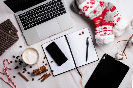 Christmas desktop with laptop, tablet and smart phone surrounded by stockings, candy canes and coffee, top view flat lay, copy space