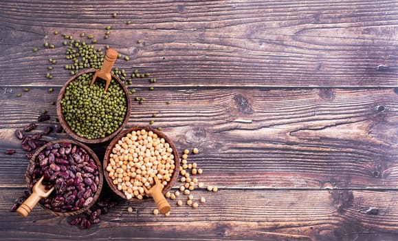 Various dried legumes in wooden bowls top view flat lay on rustic background with copy space