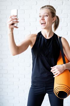 Healthy lifestyle. Sport and fitness. Young smiling fitness woman doing selfie after workout