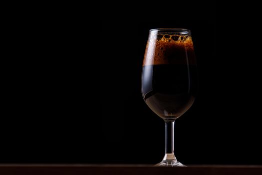 Dark beer in a glass on a dark background