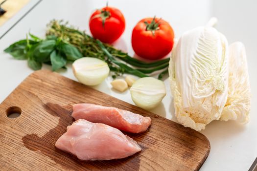 Cooking chicken tenders at home. Chicken fillet on the wooden board prepared to be cut