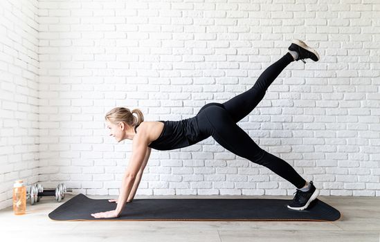 Healthy lifestyle. Sport and fitness. Young fit woman in black sportswear doing push ups at home