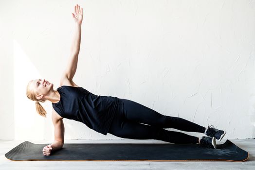 Healthy lifestyle. Sport and fitness. Young blond woman training at home in plank position