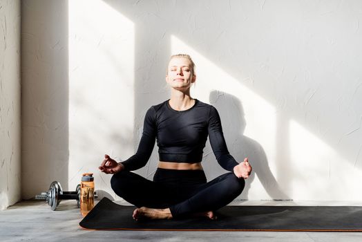 Healthy lifestyle. Sport and fitness. Young blond woman doing yoga or meditating at home