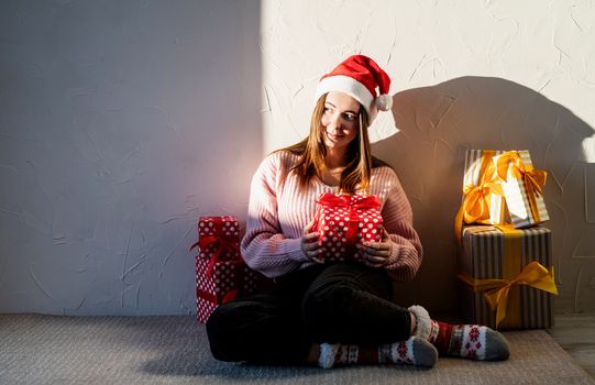 Christmas and New Year. Young woman in santa hat surrounded by presents