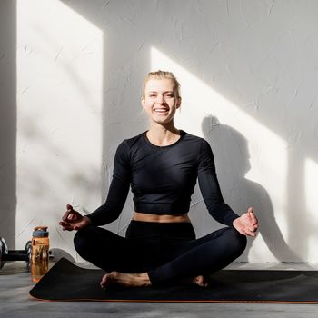 Healthy lifestyle. Sport and fitness. Young blond woman doing yoga or meditating at home