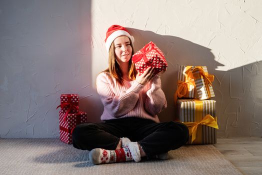 Christmas and New Year. Young woman in santa hat surrounded by presents