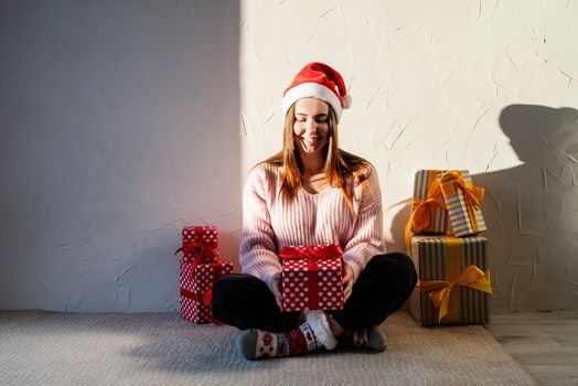 Christmas and New Year. Young woman in santa hat surrounded by presents