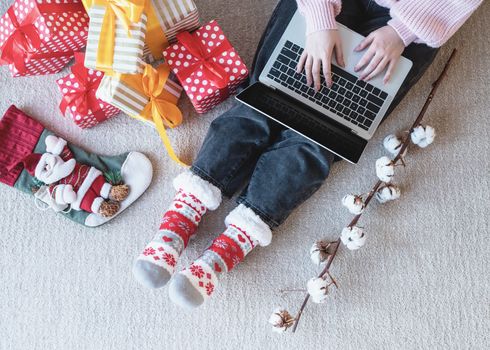 Christmas planing, online shopping concept. Young woman in santa hat shopping online surrounded by presents top view flat lay