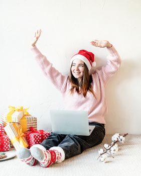 Christmas planing, online shopping concept. Young woman in santa hat shopping online surrounded by presents