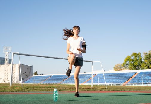 Healthy lifestyle concept. Teenager girl working out at the stadium doing high knees exercise