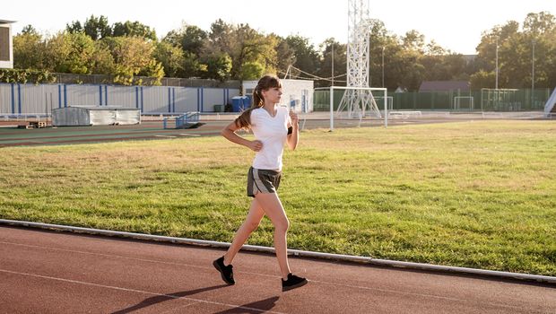 Healthy lifestyle concept. Active young woman jogging at the stadium