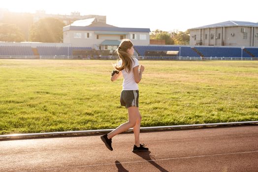 Healthy lifestyle concept. Active young woman jogging at the stadium