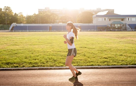 Healthy lifestyle concept. Active young woman jogging at the stadium